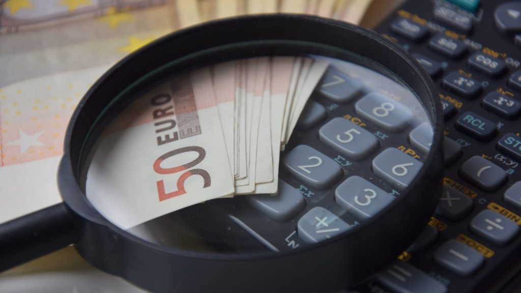Billets de 50 euros sous une loupe avec une calculatrice en arrière-plan. Financement d'Entreprise